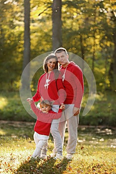 Portrait of happy family. Mom, dad and little daughter in autumn park. Young couple spending time together on vacation, outdoors.