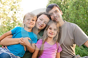 Portrait of a happy family, mother and father, son and daughter, in nature outdoor in summer.