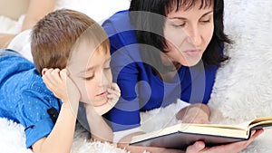 Portrait of a happy family. Mother reads a book to her child. Close-up.