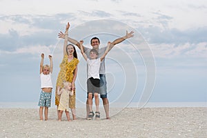 Portrait of happy family on sea beach background. Parents and three children. Family lifestyle