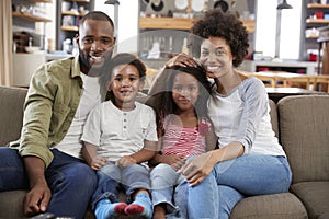 Portrait Of Happy Family Sitting On Sofa In Open Plan Lounge