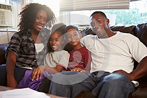 Portrait Of Happy Family Sitting On Sofa Together