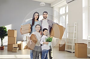 Portrait of happy family standing in their new apartment and holding cardboard boxes