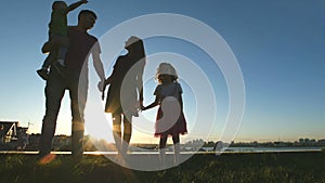 Portrait of happy family at sunset - father, mother, daughter and little son - silhouette