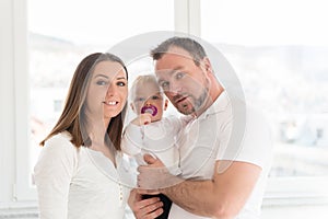Portrait of happy family of three. Parents with their beautiful baby girl at home.