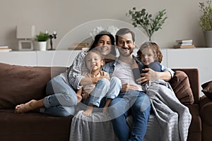 Portrait of happy family with two kids sitting on couch