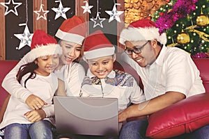 Happy family using a laptop at Christmas time