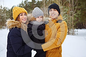 Mom and dad are cuddling and kissing their little son in winter park.