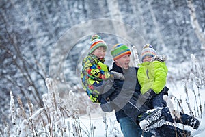 Portrait of a happy family in winter park. Father, son and little daughter laughing