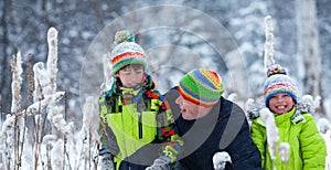 Portrait of a happy family in winter park. Father, son and little daughter laughing