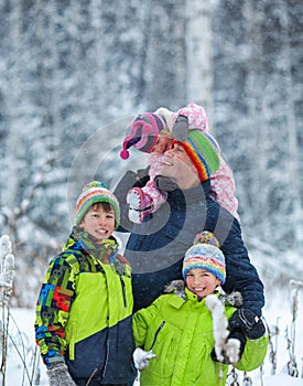 Portrait of a happy family in winter park. Father, son and little daughter laughing