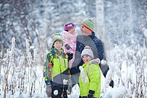 Portrait of a happy family in winter park. Father, son and little daughter laughing