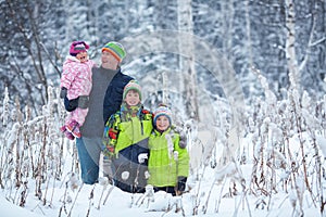 Portrait of a happy family in winter park. Father, son and little daughter laughing