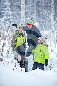 Portrait of a happy family in winter park. Father, son and little daughter laughing