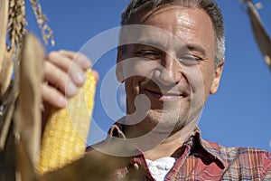 Portrait of Happy Farmer with Ripe Corncob on Corn Field