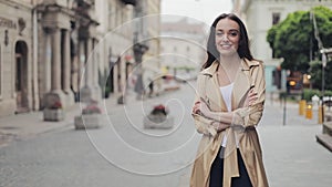 Portrait of happy fashionable beautiful young girl wearing fashionable trench smiling smiling crossing hands standing at