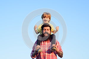 Portrait of happy father giving son piggyback ride on his shoulders. Cute boy with dad playing outdoor. Kid son hugging