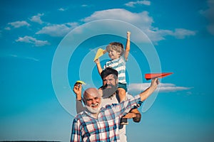 Portrait of happy father giving son piggyback ride on his shoulders and looking up. Dream of flying. Fathers day concept