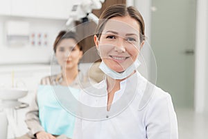 A portrait of a happy female dentist wearing lab coat, while sitting in her office