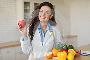 Portrait of happy female dietologist holding apple, recommending fresh fruits and vegetables, copy space