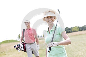 Portrait of happy female golfer with friend standing in background