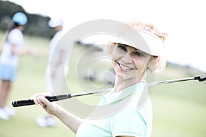 Portrait of happy female golfer holding golf club