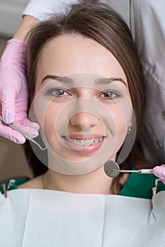 Portrait of happy female patient with metal braces. Orthodontist holding dental tools. Dentistry. Orthodontic treatment