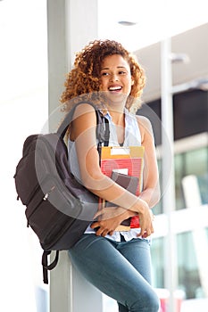 Happy female student smiling outside with bag and books photo