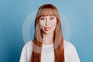 Portrait of happy foolish girl with tongue out isolated on blue background