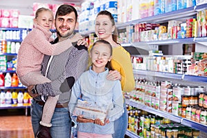 Portrait of happy friendly family of four in supermarket