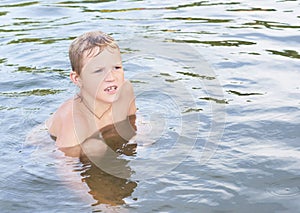 Portrait of happy fun little Caucasian boy swimming in the sea or lake.