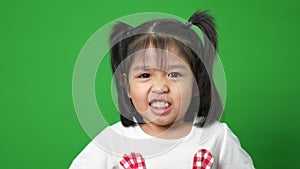 Portrait of happy and funny Asian child girl on green screen background, a child looking at camera. Preschool kid dreaming fill