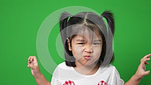 Portrait of happy and funny Asian child girl on green screen background, a child looking at camera. Preschool kid dreaming fill