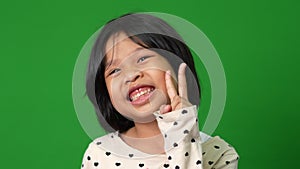 Portrait of happy and funny Asian child girl on green screen background, a child looking at camera. Preschool kid dreaming fill