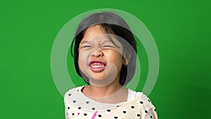 Portrait of happy and funny Asian child girl on green screen background, a child looking at camera. Preschool kid dreaming fill