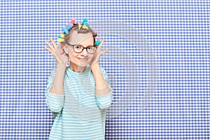 Portrait of happy funny girl with bright colorful hair curlers on head