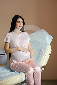 Beautiful pregnant woman sit in couch in hospital photo