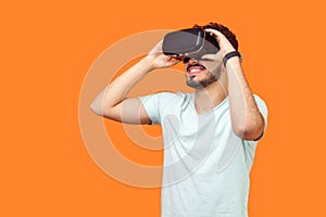 Portrait of happy gamer, brunette man playing virtual reality game. studio shot isolated on orange background