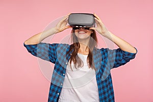 Portrait of happy gamer woman in checkered shirt wearing vr headset, playing virtual reality game