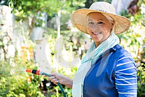 Portrait of happy gardener watering from hose at garden