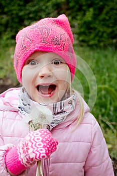 Portrait of happy girl blowing dandelion in a cold day