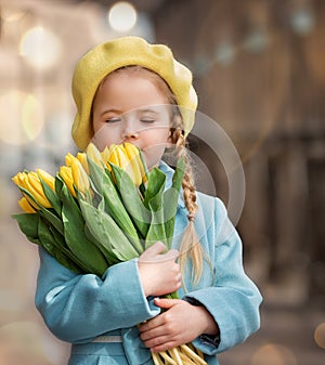 Portrait of a happy girl with a bouquet of yellow tulips on a walk in spring