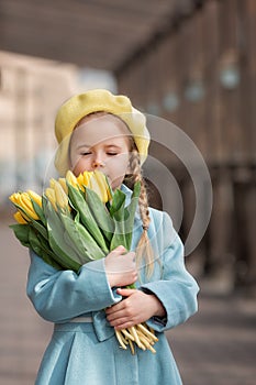 Portrait of a happy girl with a bouquet of yellow tulips on a walk in spring.