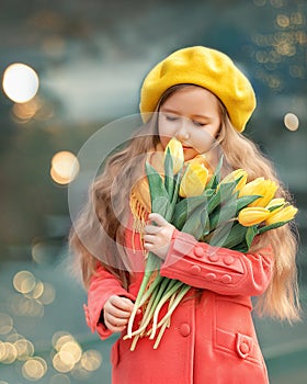 Portrait of a happy girl with a bouquet of yellow tulips on a walk in spring. Flowers for International Women's Day.