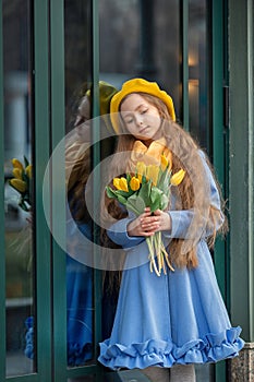 Portrait of a happy girl with a bouquet of yellow tulips on a walk in spring. Flowers for International Women& x27;s Day.