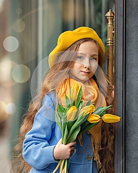 Portrait of a happy girl with a bouquet of yellow tulips on a walk in spring. Flowers for International Women& x27;s Day.