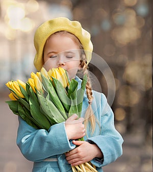 Portrait of a happy girl with a bouquet of yellow tulips on a walk in spring. Flowers for International Women& x27;s Day.