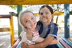 Portrait of happy girl embracing while sitting on jungle gym