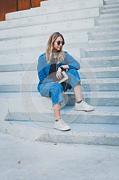 Portrait of a happy girl listening music on line with headphones from a smartphone in the street in a summer sunny day. Woman list