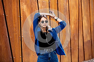 Portrait of a happy girl listening music on line with headphones from a smartphone in the street in a summer sunny day. Woman list